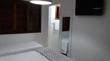 Een slaapkamer met twee bedden, een spiegel en een televisie aan de muur.