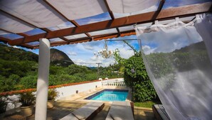 A pool area with lounge chairs, a pergola, and a view of a mountainous landscape. - Pousada do Lago Petrópolis (Petrópolis)
