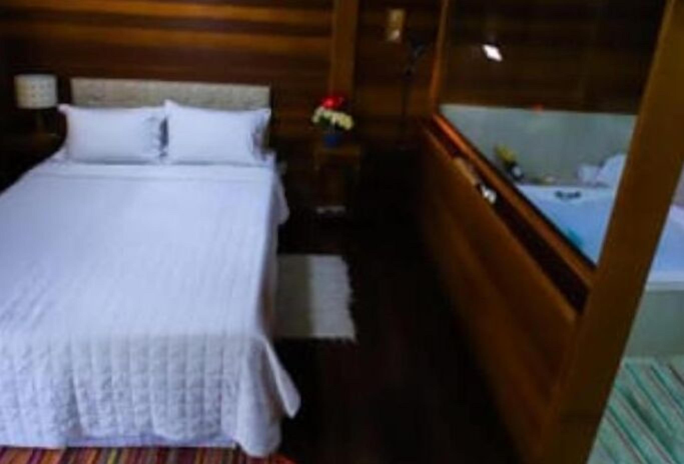 A wooden-framed room with a bed, a nightstand, and a window.