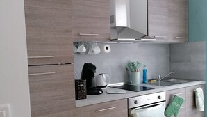 Eine moderne Küche mit grauen Schränken, einem Einbauofen, einer Kaffeemaschine und einem Spülbecken.