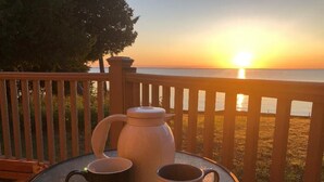 A table with two coffee mugs and a white coffee pot on a balcony overlooking a sunset. - Pure Michigan on Lake Michigan-Manistique, miles of sandy beach fun (Manistique)