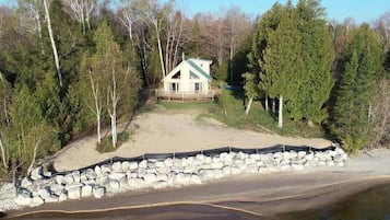 Situated in a wooded area, this cottage features a gabled roof and a front deck.