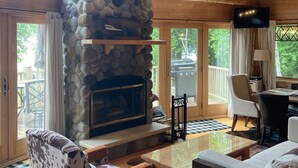 A cozy lodge interior with a stone fireplace, wooden beams, and a mounted deer head. - Pure Michigan on Lake Michigan-Manistique, miles of sandy beach fun (Manistique)