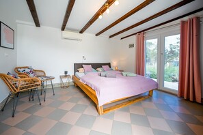 A bedroom with a wooden bed, two wicker chairs, a small table, and a window with curtains.