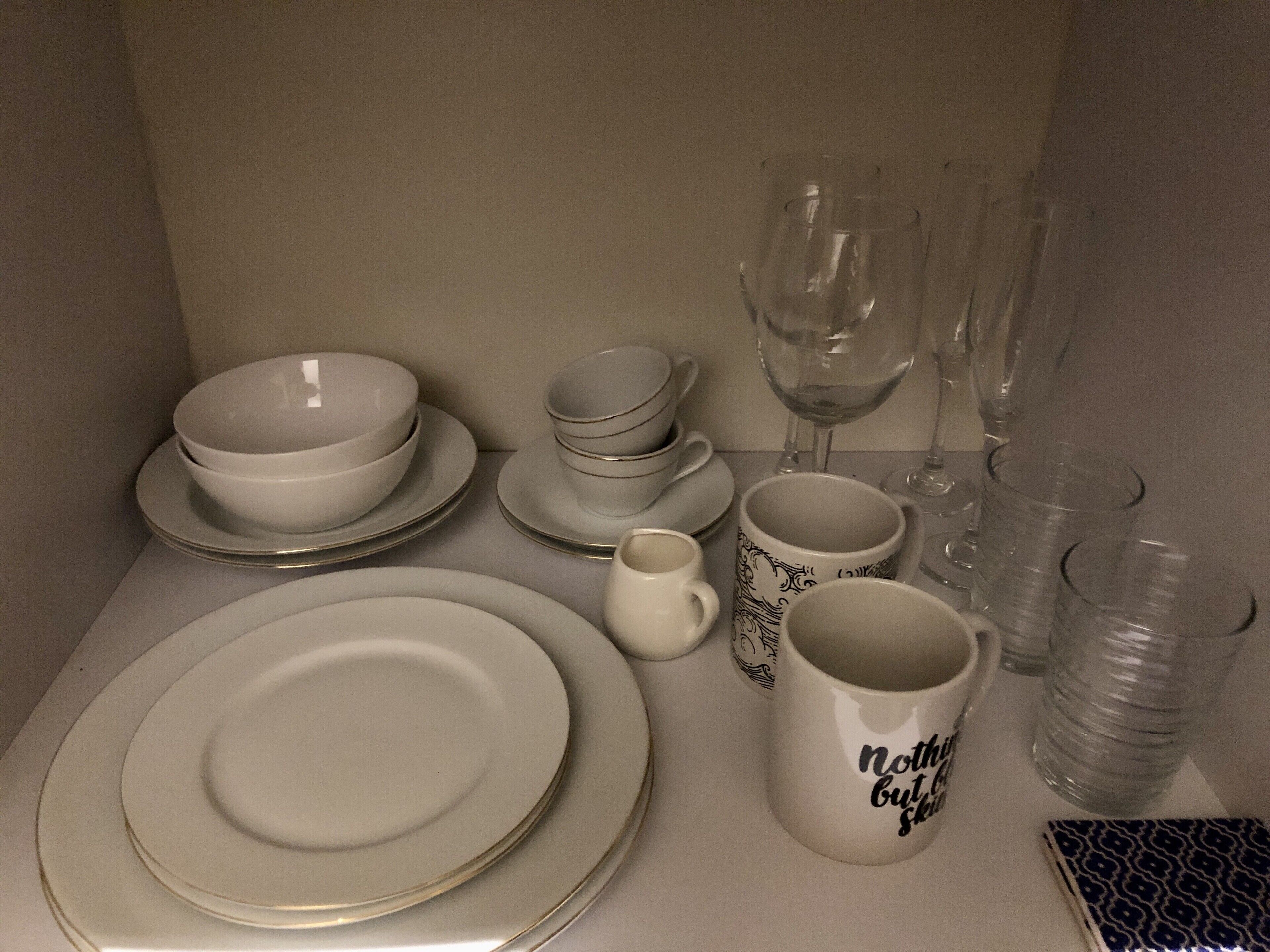 Una mesa servida con platos, tazones, tazas y una jarra.