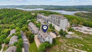 An aerial view of a residential area with multi-story buildings, a large body of water, and surrounding greenery. - Fantastic Lake Views, Large Deck, Boat Slip Included & Free SDC Tickets (Branson)