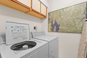 Un espace buanderie comprenant un lave-linge, un étendoir et une carte accrochée au mur.
