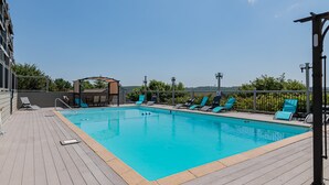 A rectangular swimming pool with a wooden deck, surrounded by lounge chairs and a covered seating area. - Fantastic Lake Views, Large Deck, Boat Slip Included & Free SDC Tickets (Branson)