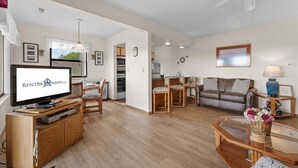A living room with a TV, wooden furniture, a dining area, a sofa, and a ceiling fan. - Fantastic Lake Views, Large Deck, Boat Slip Included & Free SDC Tickets (Branson)