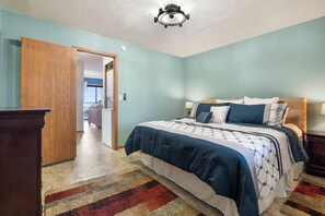 Un dormitorio con una cama, un armario de madera, una alfombra y una lámpara en el techo.