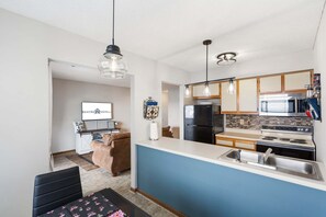 A modern kitchen with a blue countertop, stainless steel appliances, and pendant lighting. - Stunning Table Rock Lake View Condo, Newly Renovated with Free SDC Tickets (Branson)