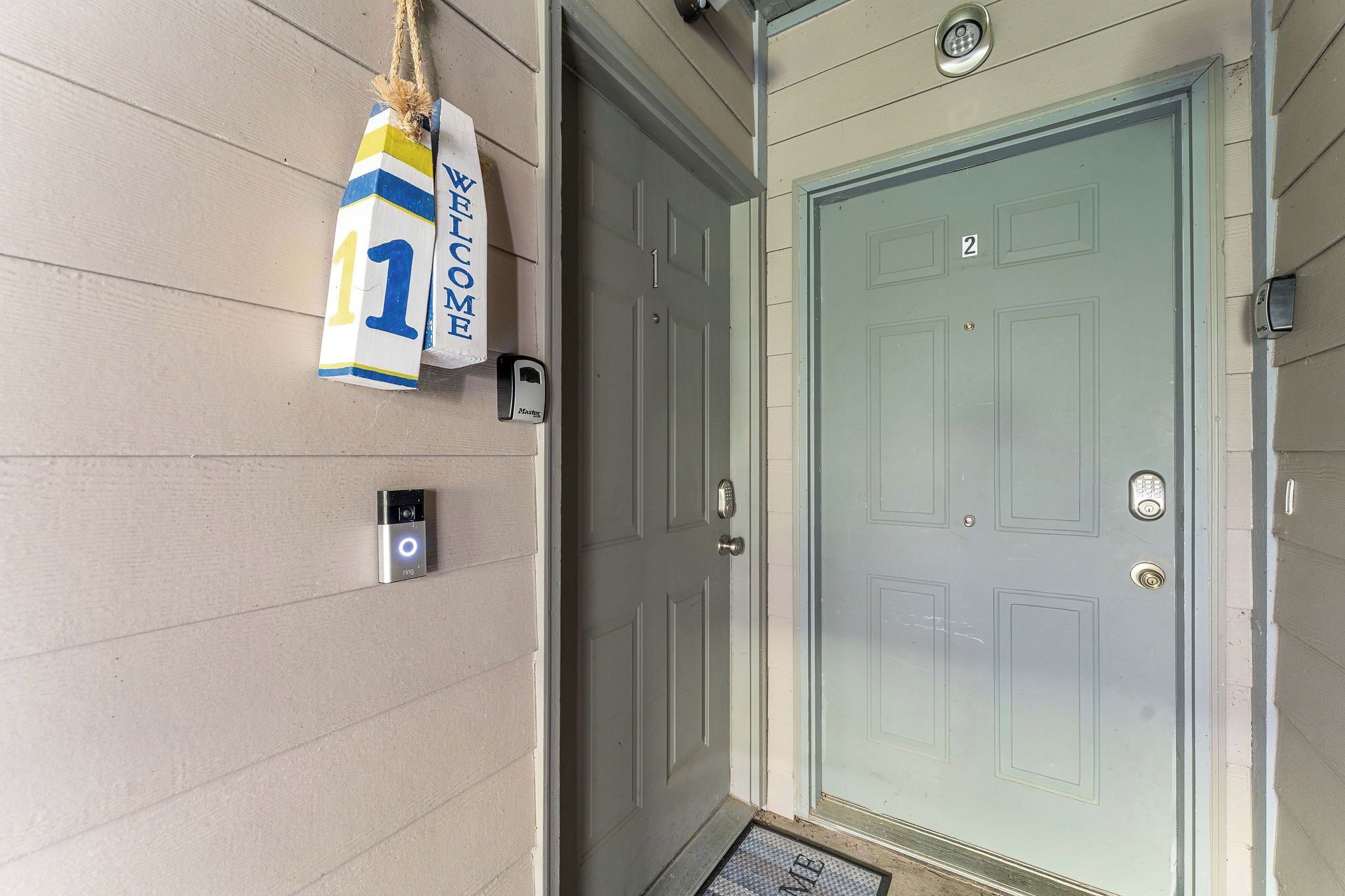 Une porte avec une plaque portant un numéro, un interphone et une caméra de surveillance.