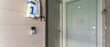 Une porte avec une plaque portant un numéro, un interphone et une caméra de surveillance.