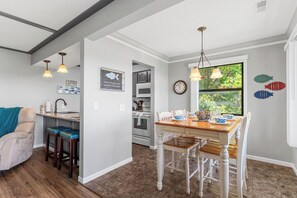 A kitchen with a dining table, bar stools, pendant lights, and a view through a window. - Next to Silver Dollar City: Lake Condo with Stunning Table Rock Views & Tickets (Branson)