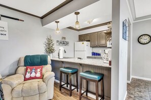 Eine moderne Küche mit Bar, Holzstühlen und einer gemütlichen Sitzecke mit Sessel und Zierkissen.