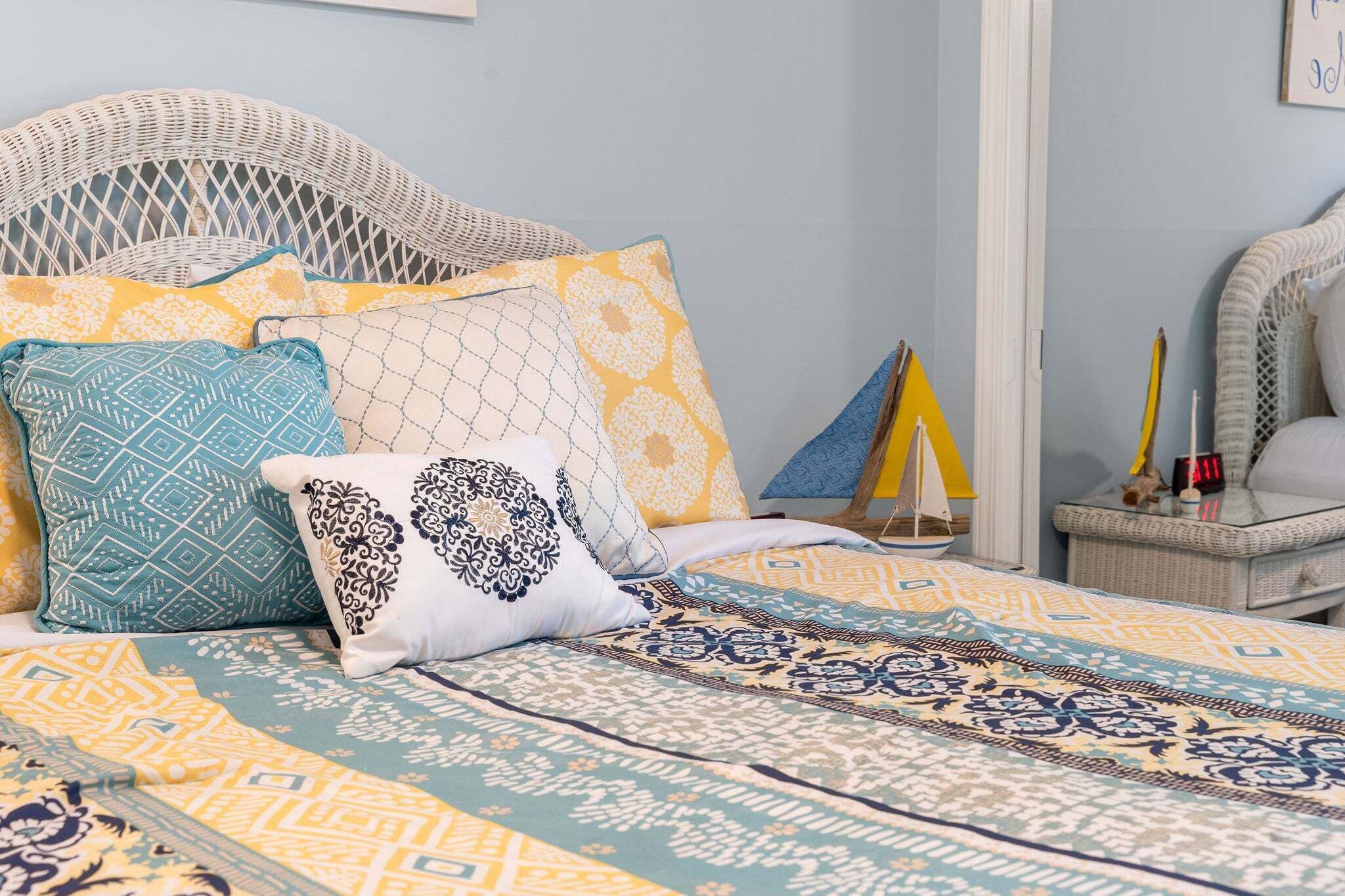 A bed with patterned bedding and a wicker headboard.