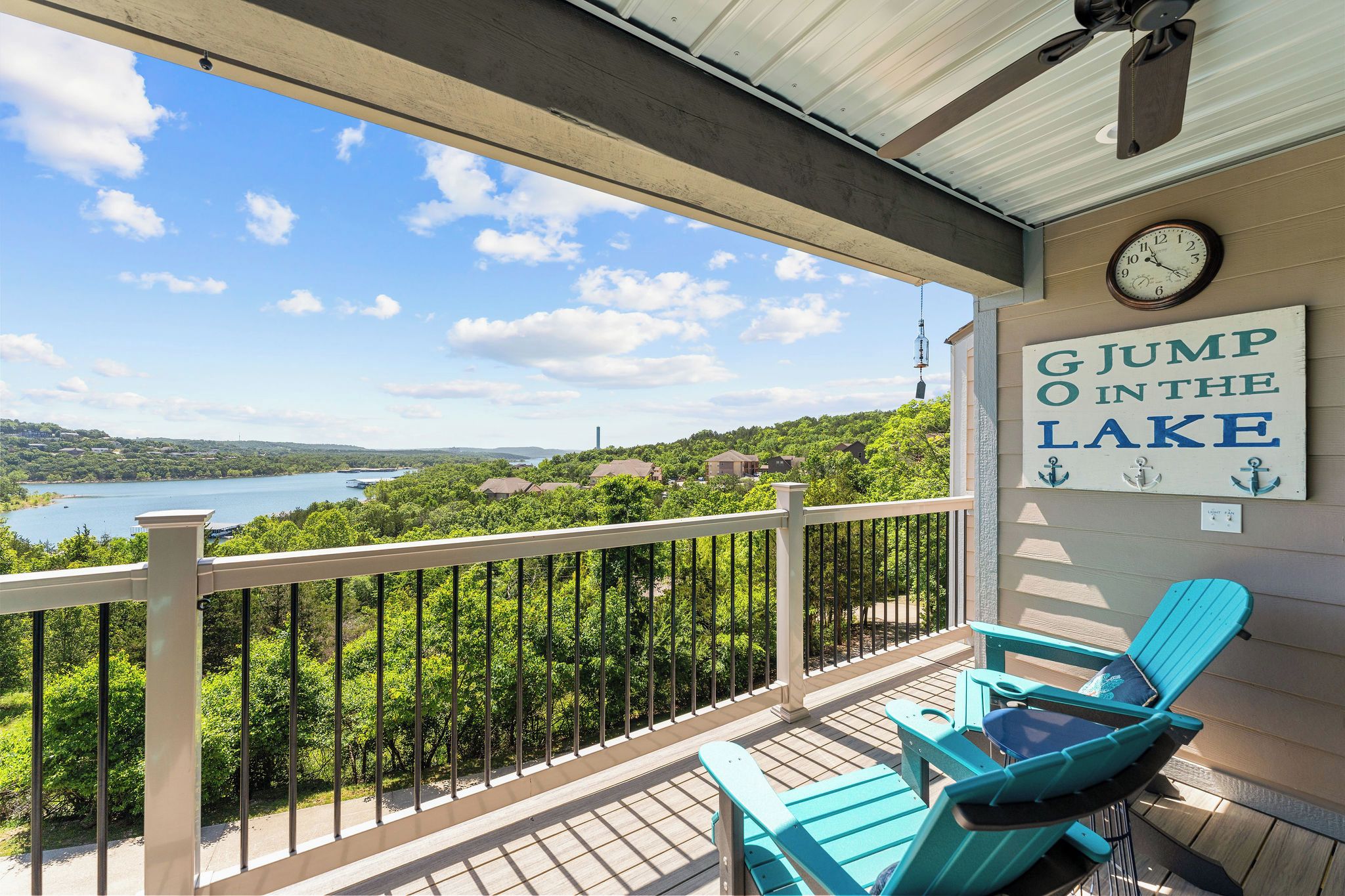 A balcony with a view of a lake, a clock, and a sign that reads 'G Jump in the Lake.'