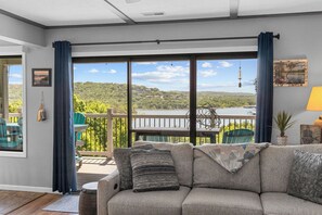 A living room with a sofa, a view of a lake, and a balcony with outdoor furniture. - Next to Silver Dollar City: Lake Condo with Stunning Table Rock Views & Tickets (Branson)