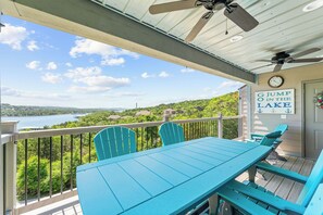 Un balcon avec une table et des chaises, un ventilateur de plafond et une pancarte sur laquelle on peut lire : « G, saute dans le lac ! »