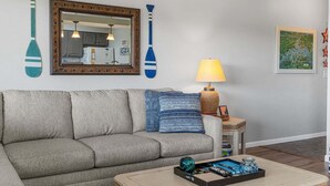 Ett vardagsrum med en soffa, en lampa, ett soffbord och väggdekorationer, inklusive en spegel och två föremål formade som paddlar.
