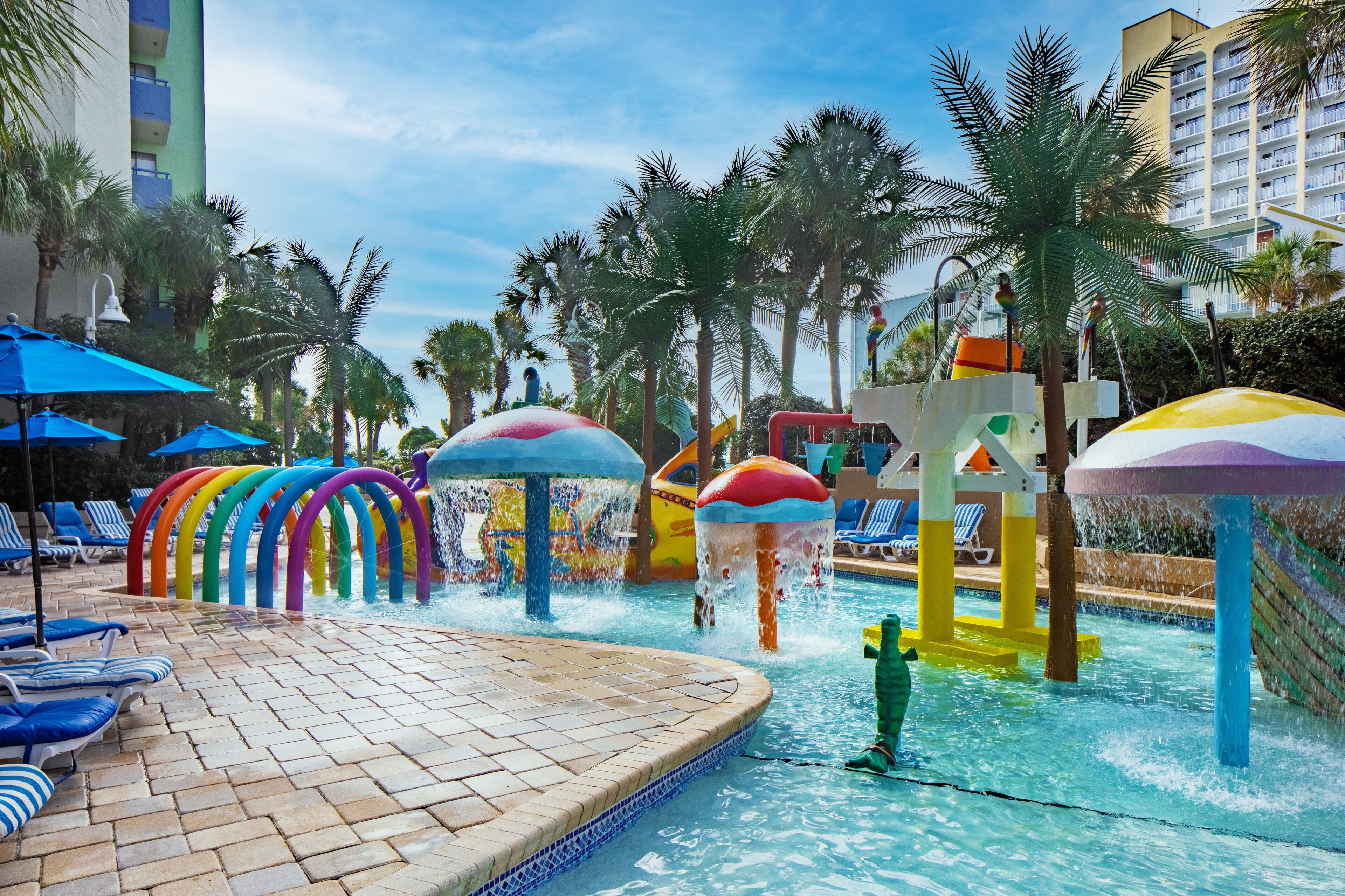 A pool area with colorful water features and lounge chairs.