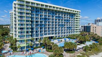 Un hôtel à plusieurs étages doté de balcons, d’une piscine et d’un espace de plage.
