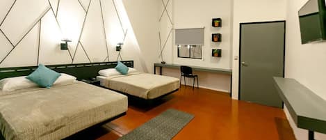 A hotel room with two beds, a desk, a chair, and a door.