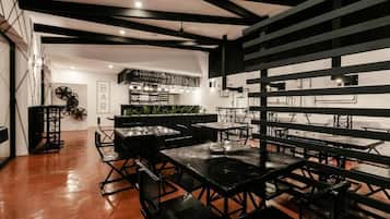 Un bar moderno con mesas negras y un techo rústico.