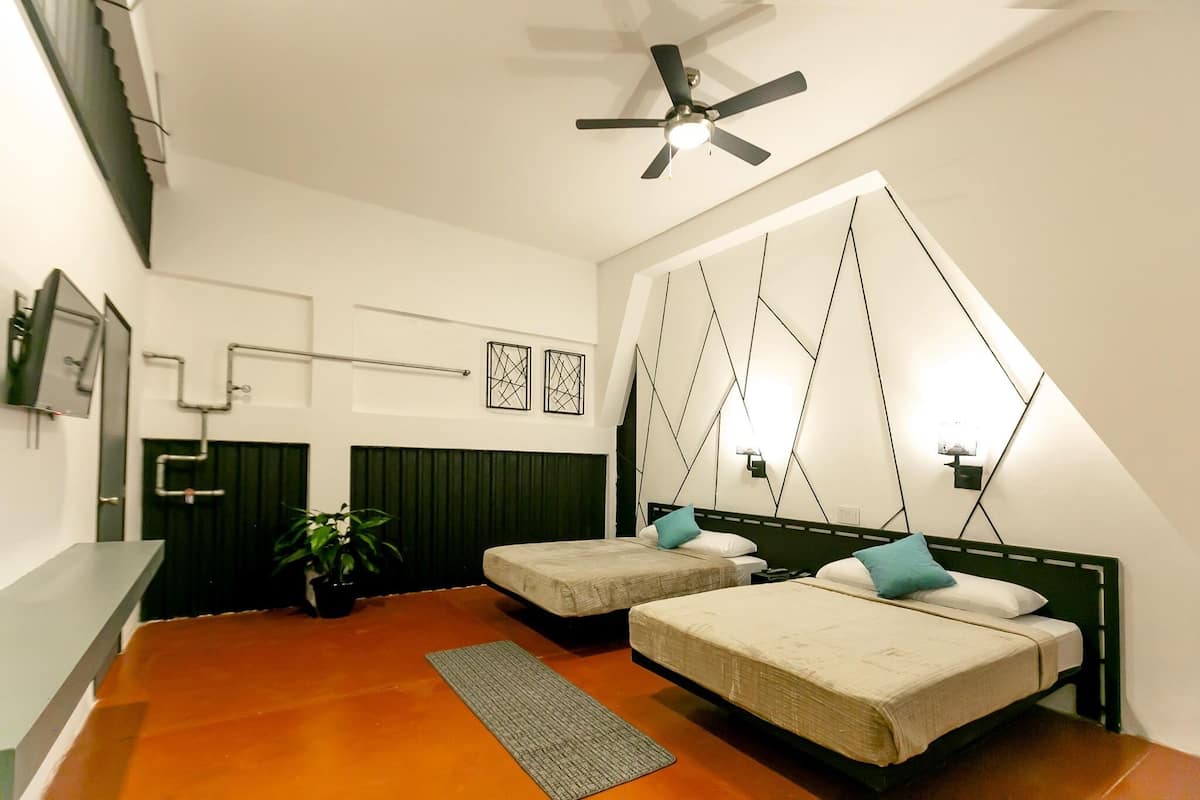 A modern bedroom with two beds, a ceiling fan, and a large window.