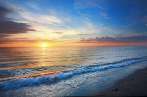 A beach scene with the sun setting over the ocean, waves gently lapping at the shore. - 2 minutes from beautiful Siesta Key mainbeach! (Siesta Key)
