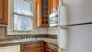 A kitchen with wooden cabinets, a stainless steel sink, and a built-in refrigerator. - Charming Carriage House, Heated Pool Access (Savannah)