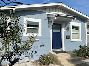 A single-story house with a blue door, white trim, and a small porch.