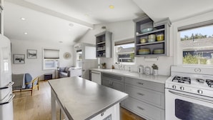 A modern kitchen with a central island, built-in shelves, and a large window. - 30-Night Minimum Downtown HB - 1/2 mile to beach, Pier, Main St, & Pacific City (Huntington Beach)