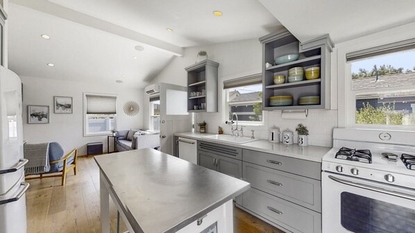A modern kitchen with a central island, built-in shelves, and a large window.
