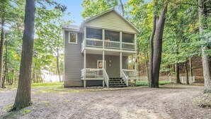A two-story cabin with a balcony, surrounded by trees. - NEW Scenic Lake Michigan House w/ Direct Access to Private Beach (Manistee)