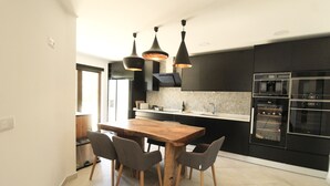 Eine moderne Küche mit einem Holztisch, schwarzen Schränken und Edelstahlgeräten.