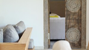 Ein modernes Zimmer mit einer Holzbank, einem Bett mit weißem Kopfteil und einer dekorativen Wandverkleidung.