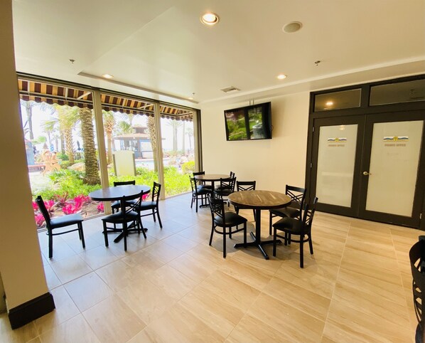 A hotel room with a large window, a flat-screen TV mounted on the wall, and a private office door.