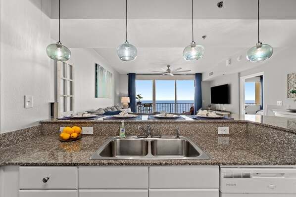 Una cocina moderna con una isla grande, pileta doble y vista al mar.