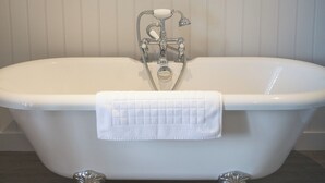 A freestanding bathtub with a white towel, wooden panel wall, and starfish decorations. - Test property Compliance 1 (Kula)