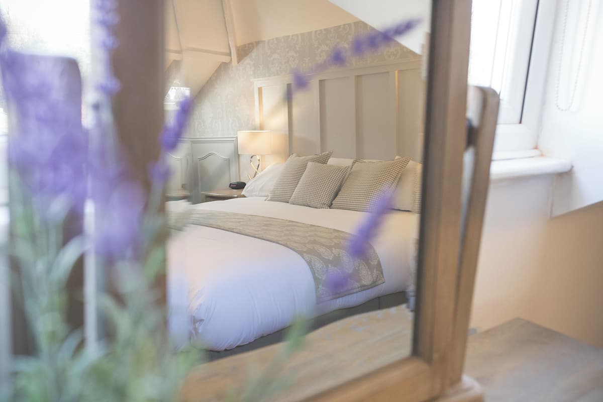 Ein Schlafzimmer mit Bett, Nachttisch, Lampe und Fenster.