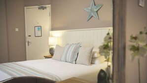 A neatly made bed with striped bedding, a star decoration on the wall, and a bedside lamp. - Test property Compliance 1 (Kula)