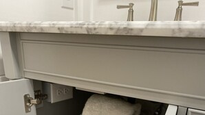 A bathroom with a marble countertop, a sink with two faucets, and a towel rack with neatly folded towels.