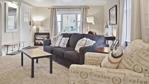 A living room with a sofa, a coffee table, and a bookshelf. - Ivywild Bungalow ↠Close to Trails/Downtown/Shops↞ (Colorado Springs)