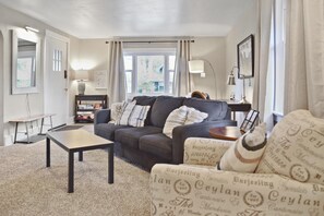 A living room with a sofa, a coffee table, and a bookshelf. - Ivywild Bungalow ↠Close to Trails/Downtown/Shops↞ (Colorado Springs)