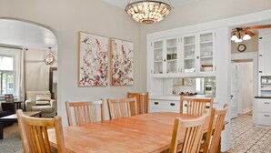 A dining area with a wooden table and chairs, surrounded by white cabinets and a chandelier. - Ivywild Bungalow ↠Close to Trails/Downtown/Shops↞ (Colorado Springs)