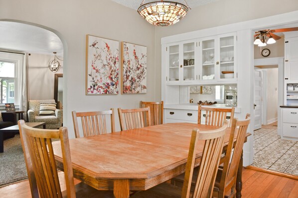 A dining area with a wooden table and chairs, surrounded by white cabinets and a chandelier. - Ivywild Bungalow ↠Close to Trails/Downtown/Shops↞ (Colorado Springs)