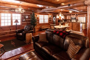 A log cabin interior with a leather sofa, dining table, and kitchen area. - Cozy, Rustic Luxury Cabin on Round Lake, with all of the modern conveniences! (Hayward)
