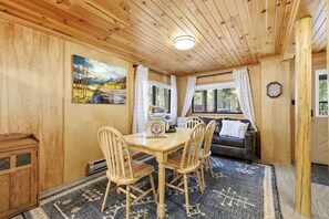 Un intérieur en bois comprenant une table à manger, des chaises, un canapé et un tableau accroché au mur.