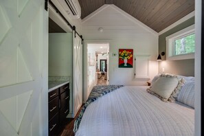 Een slaapkamer met een groot bed, een kaptafel, een bloemen schilderij en een raam met uitzicht.